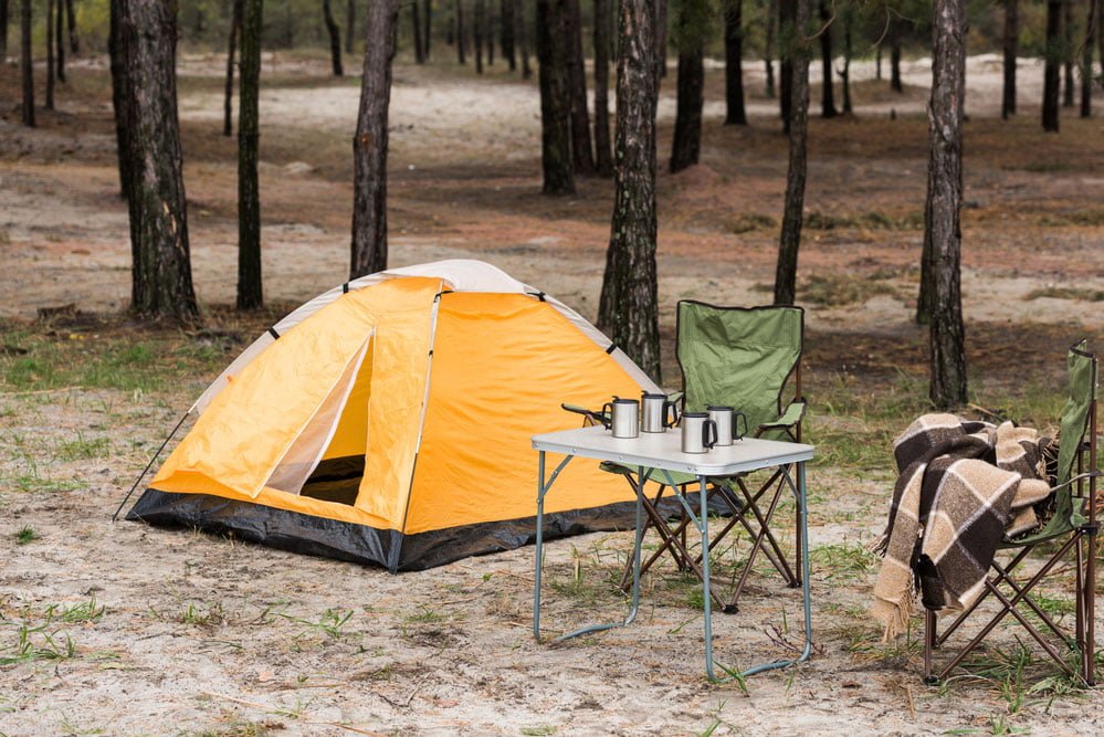 Campingstühle neben einem Zelt im Wald