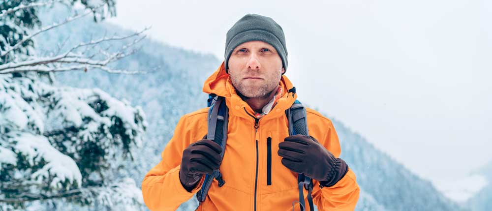 Mann im Schnee mit Softshell Jacke in Orange