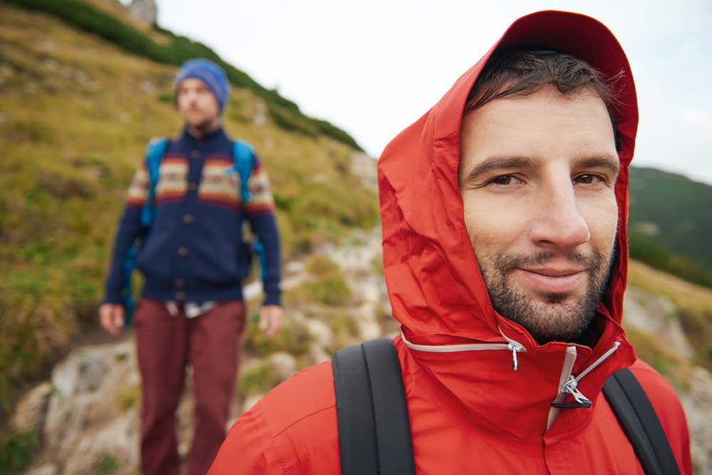 Mann mit roter Softshelljacke beim Wandern