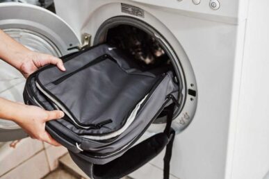 Rucksack wird in die Waschmaschine gesteckt zum Waschen