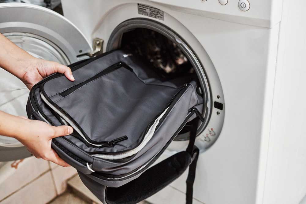 Rucksack wird in die Waschmaschine gesteckt zum Waschen